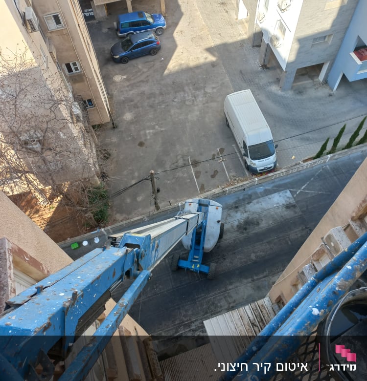 מנוף כחול ליד בניין גבוה עם פלטפורמה